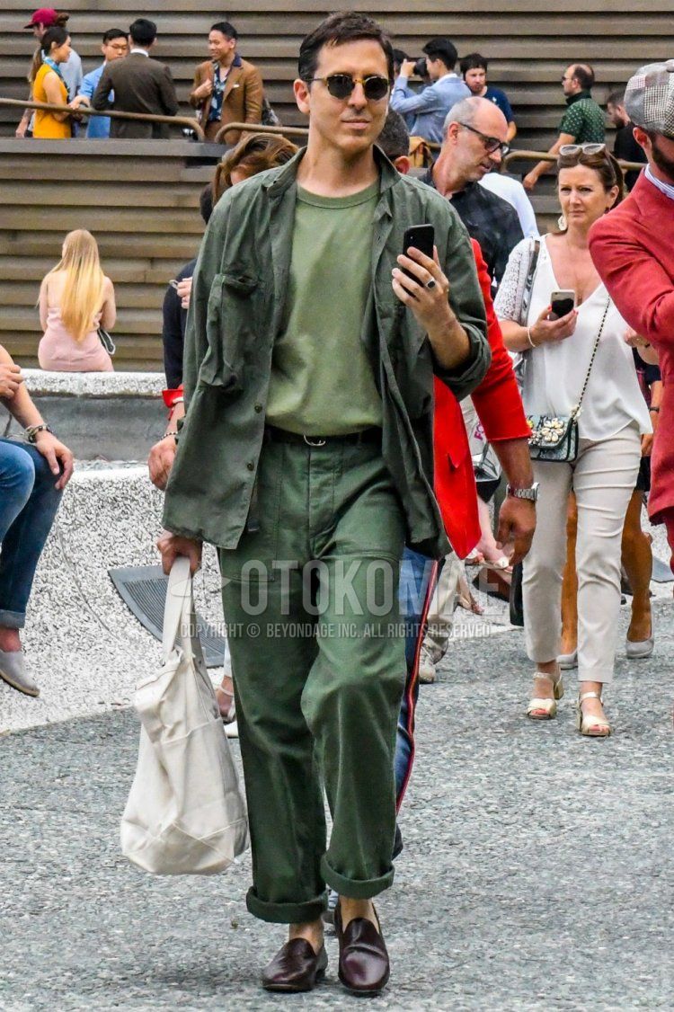 Men's spring/summer/fall outfit with beige tortoiseshell sunglasses, olive green solid shirt, olive green solid t-shirt, black solid leather belt, olive green solid cargo pants, olive green solid chinos, brown loafer leather shoes.