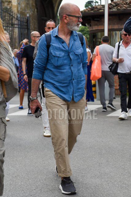 Men's summer coordinate and outfit with plain black glasses, plain blue denim/chambray shirt, plain beige chinos, and black low-cut sneakers.