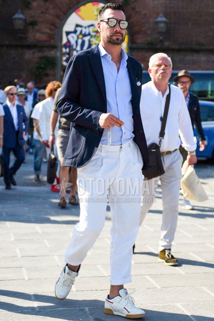Men's spring, summer, and fall coordinate and outfit with plain black sunglasses, plain navy tailored jacket, plain light blue shirt, plain white cotton pants, and white low-cut sneakers.