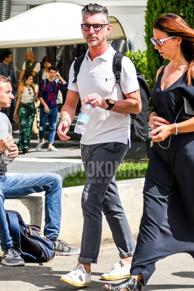 A summer men's coordinate and outfit with plain glasses, a Polo Ralph Lauren plain white polo shirt, plain gray denim/jeans, and Philip Model white low-cut sneakers.