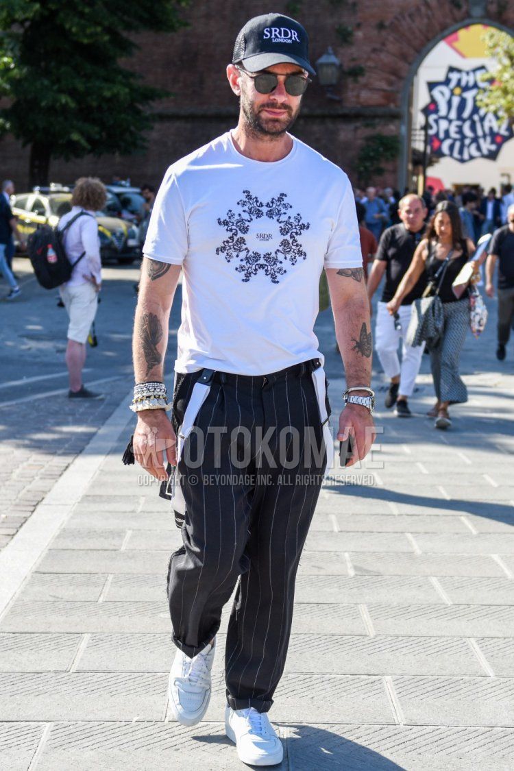 Men's spring/summer coordinate and outfit with black one-point baseball cap, plain black sunglasses, white graphic t-shirt, plain white suspenders, plain black slacks, and white low-cut sneakers.