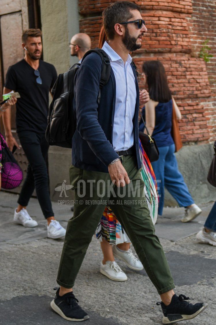 Spring and fall men's coordinate and outfit with plain navy sunglasses, plain dark gray cardigan, plain white shirt, plain black mesh belt, plain olive green chinos, Adidas NMD black low-cut sneakers, and plain black backpack.