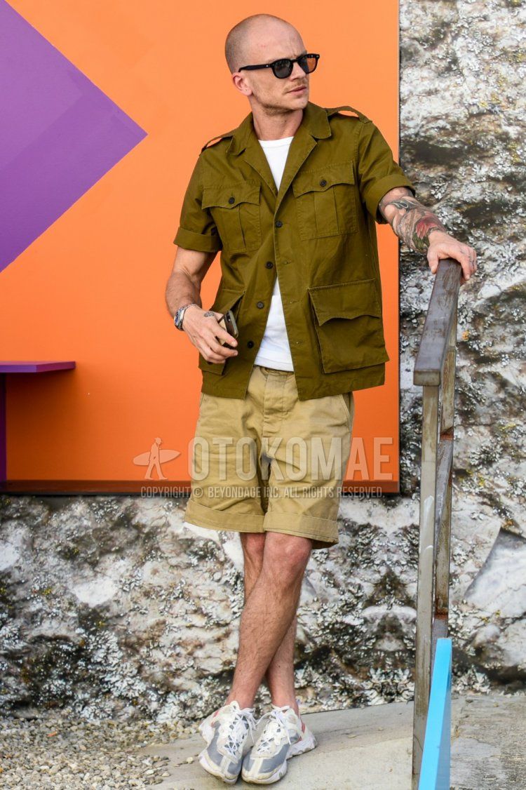 Summer men's coordinate and outfit with plain sunglasses, plain olive green shirt, plain white t-shirt, plain beige chinos, plain shorts and React Element 87 Nike white low-cut sneakers.
