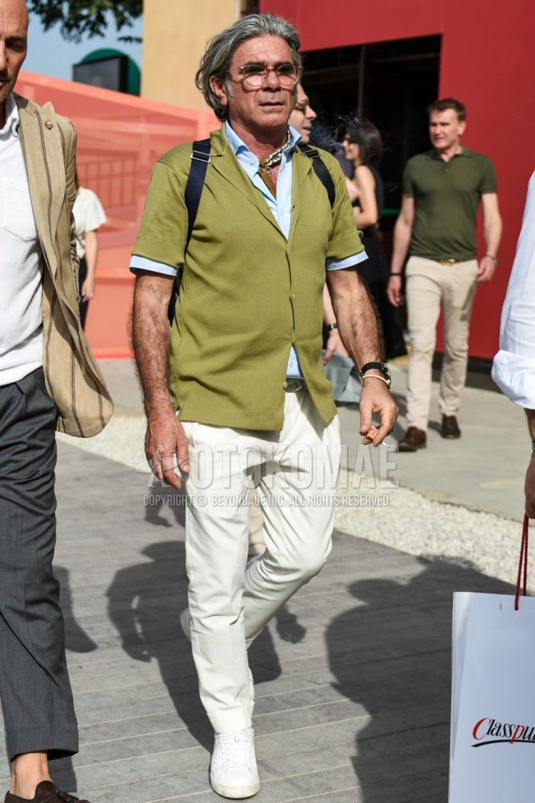 Men's summer coordinate and outfit with plain glasses, plain olive green cardigan, short-sleeved plain light blue shirt, plain white chinos, and white low-cut sneakers.
