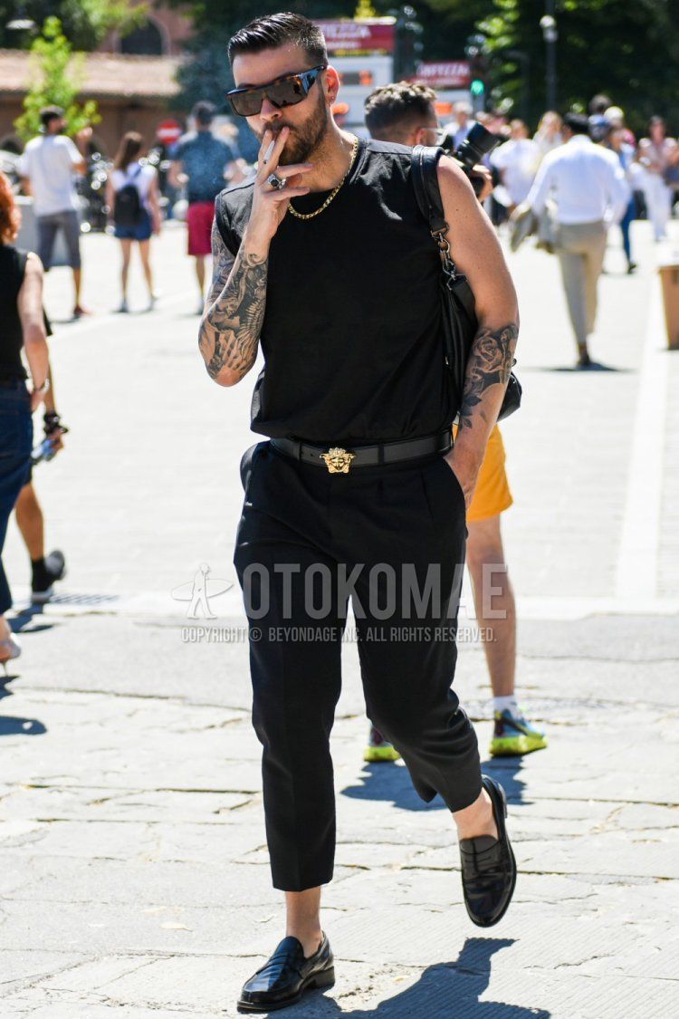 Summer men's coordinate and outfit with brown tortoiseshell sunglasses, plain black tank top, plain black leather belt, plain black slacks, plain cropped pants, black coin loafer leather shoes, and plain black shoulder bag.