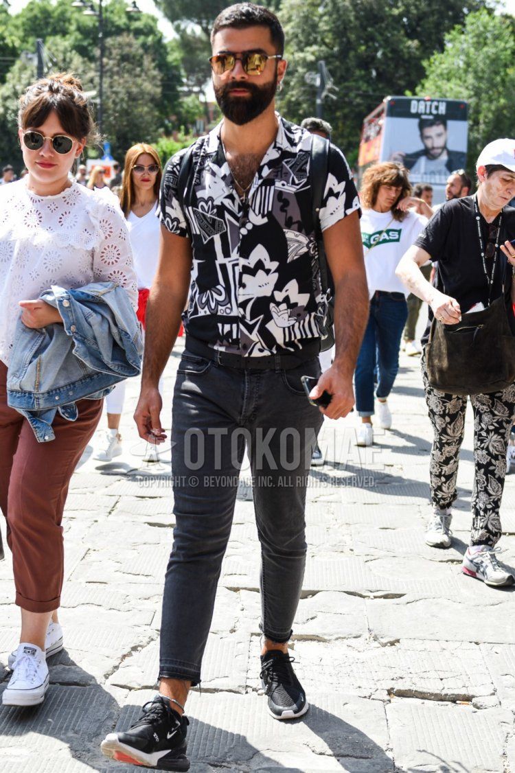 Summer men's coordinate and outfit with gold/black solid color sunglasses, black/white top/inner shirt, dark gray solid color denim/jeans, and black low-cut Air Max 270 sneakers.
