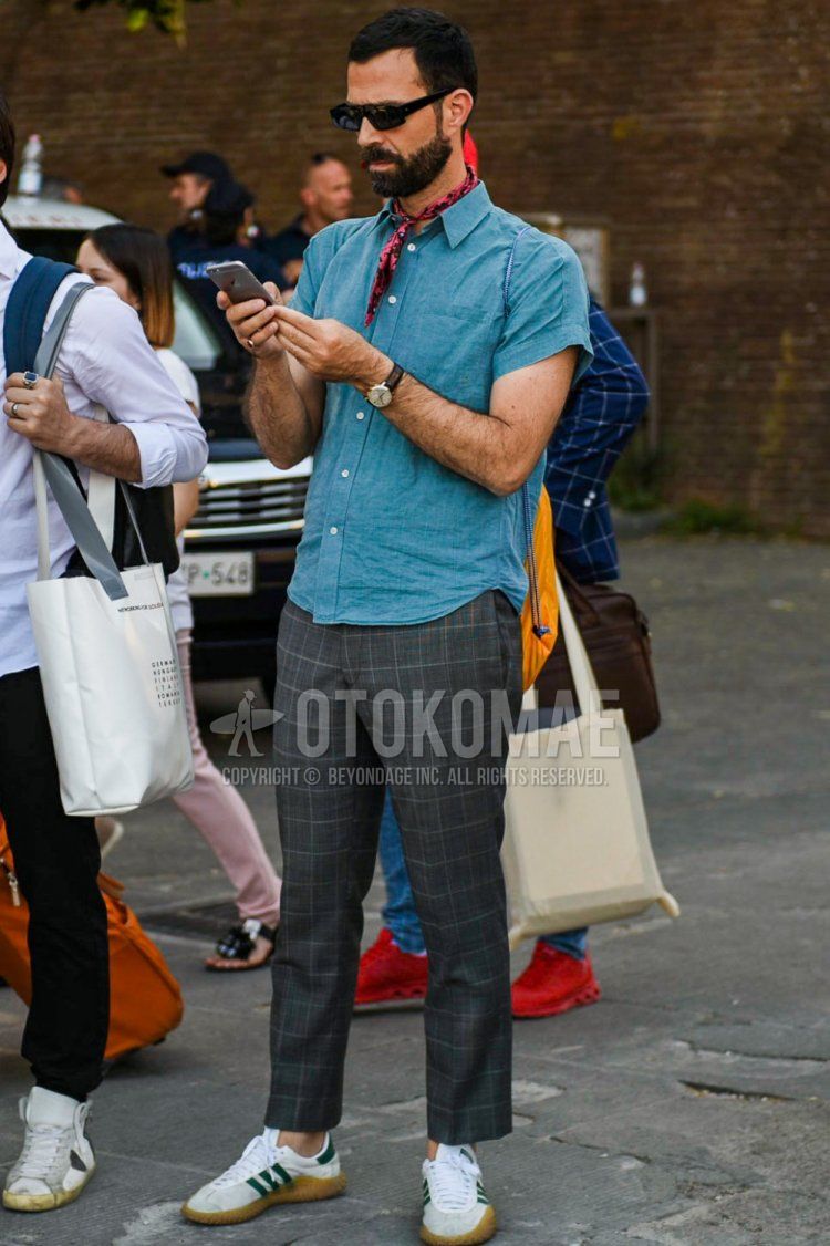 Men's summer coordinate and outfit with plain black sunglasses, black/red stole bandana/neckerchief, short-sleeved plain light blue shirt, gray checked slacks, and white low-cut Adidas sneakers.