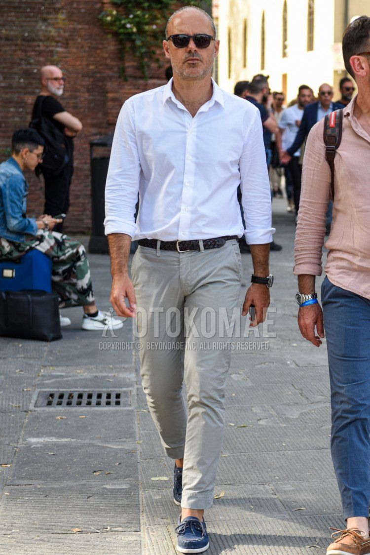 Men's spring/summer coordinate and outfit with plain black Wellington sunglasses, plain white shirt, plain black mesh belt, plain black leather belt, plain beige chinos, and navy moccasins/deck shoes leather shoes.