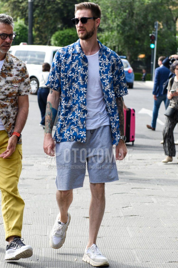 Summer men's coordinate and outfit with Wellington plain black sunglasses, blue top/inner shirt, plain white t-shirt, plain gray shorts, and white low-cut sneakers.