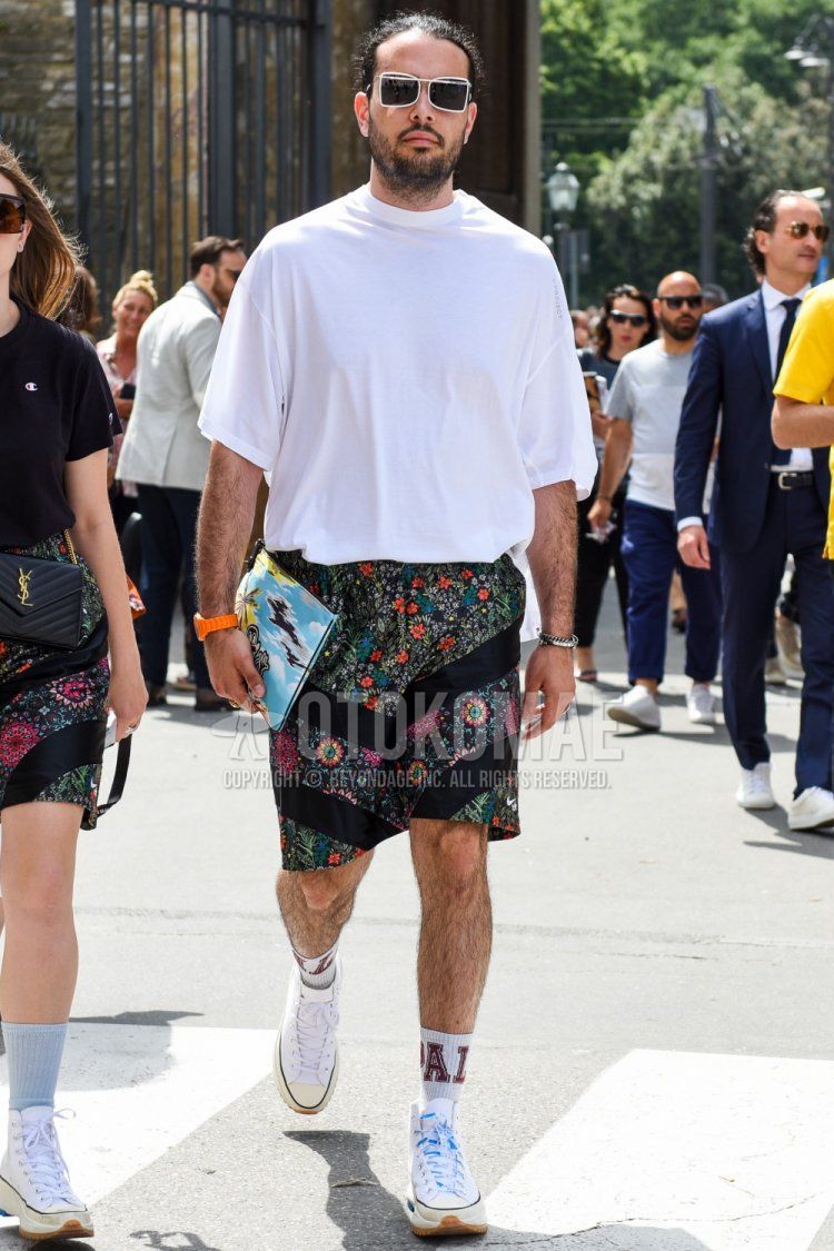 A summer men's coordinate and outfit with plain white sunglasses, plain white t-shirt, multi-colored bottoms shorts, plain white socks, and white low-cut sneakers.