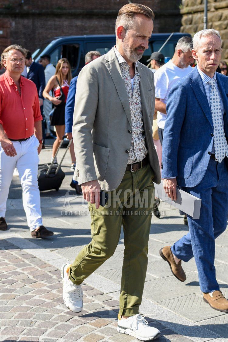Men's spring, summer, and fall coordinate and outfit with plain gray tailored jacket, white top/inner shirt, plain brown leather belt, plain olive green chinos, and white low-cut sneakers.