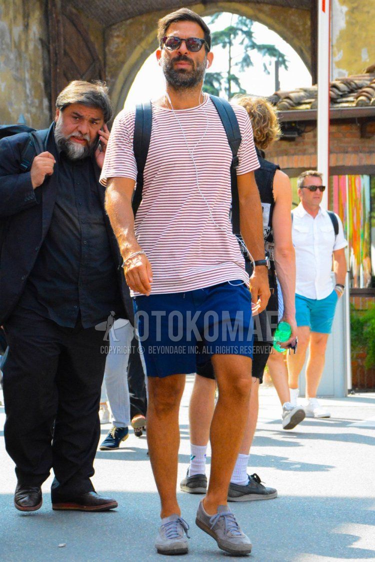 Men's summer coordinate and outfit with plain sunglasses, red striped t-shirt, plain blue shorts, and gray low-cut sneakers.