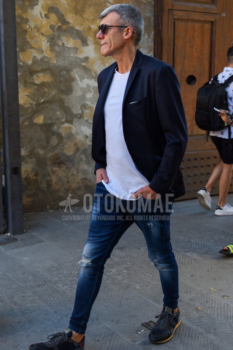 Men's spring, summer, and fall coordinate and outfit with plain black sunglasses, plain navy tailored jacket, plain white t-shirt, plain blue damaged jeans, and gray low-cut sneakers.