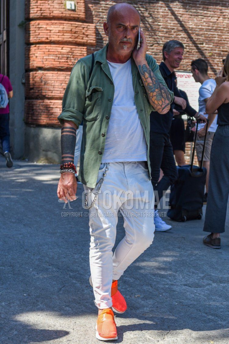 Men's spring, summer, and fall coordinate and outfit with olive green solid shirt jacket, solid white t-shirt, solid white denim/jeans, and orange low-cut sneakers.