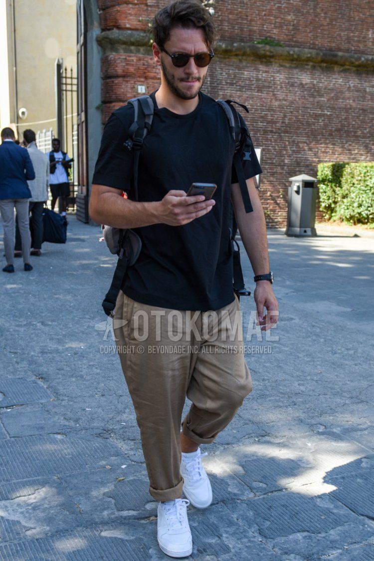 Men's summer coordinate and outfit with plain black sunglasses, plain black t-shirt, plain beige cotton pants, and white low-cut sneakers.