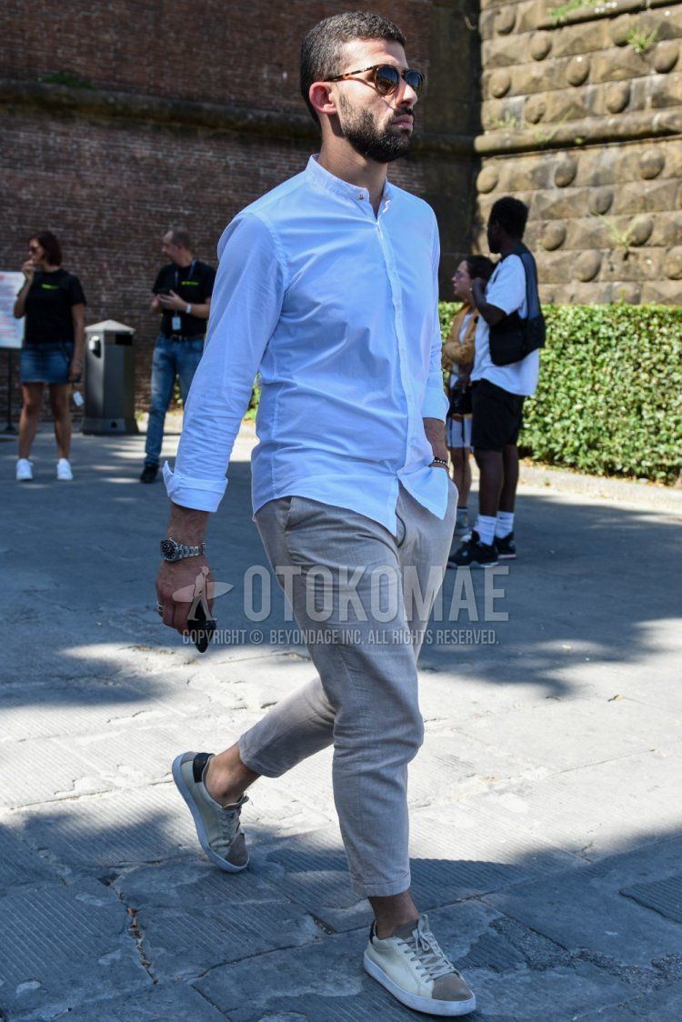 Men's spring/summer coordinate and outfit with brown tortoiseshell sunglasses, band collar plain white shirt, linen plain beige slacks, plain beige cropped pants, and beige/white low-cut sneakers.
