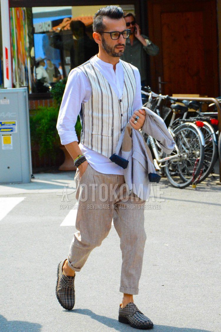 Men's spring/summer coordinate and outfit with plain black glasses, plain white shirt with band collar, white striped gilet, plain beige slacks, and beige plain-toe leather shoes.