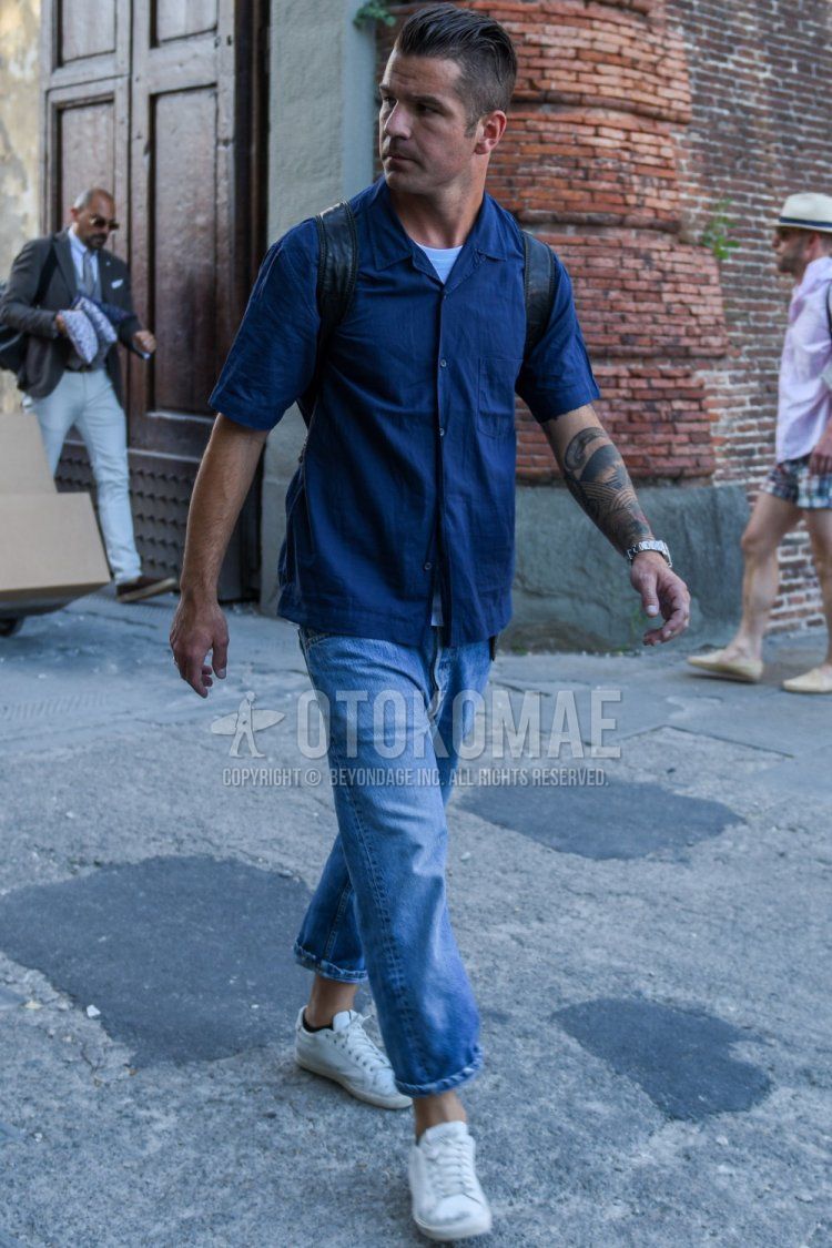 Summer men's coordinate and outfit with short sleeves open collar dark gray solid shirt, solid white t-shirt, solid blue denim/jeans, solid blue cropped pants, and white low-cut sneakers.