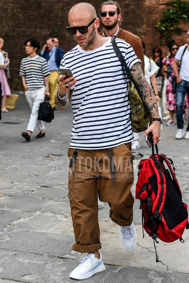 Men's summer coordinate and outfit with plain sunglasses, white striped t-shirt, plain brown cotton pants, and white low-cut sneakers.