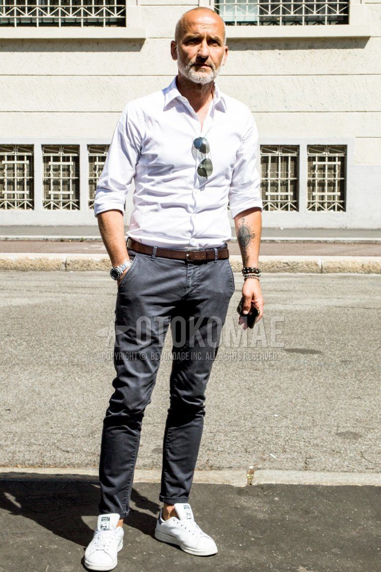 Men's spring/summer coordinate and outfit with plain sunglasses, plain white shirt, plain brown leather belt, plain gray chinos, and Adidas Stan Smith white low-cut sneakers.
