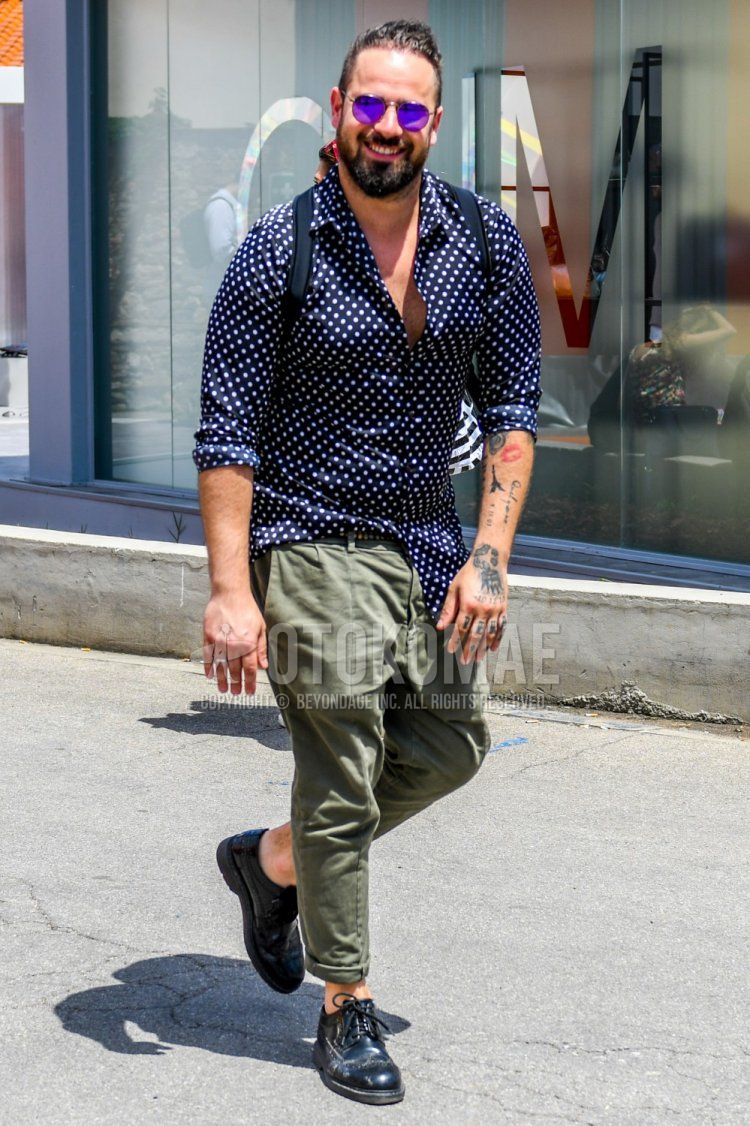 Men's spring and summer coordinate and outfit with plain sunglasses, black dotted shirt, plain green chinos, and black brogue shoes leather shoes.