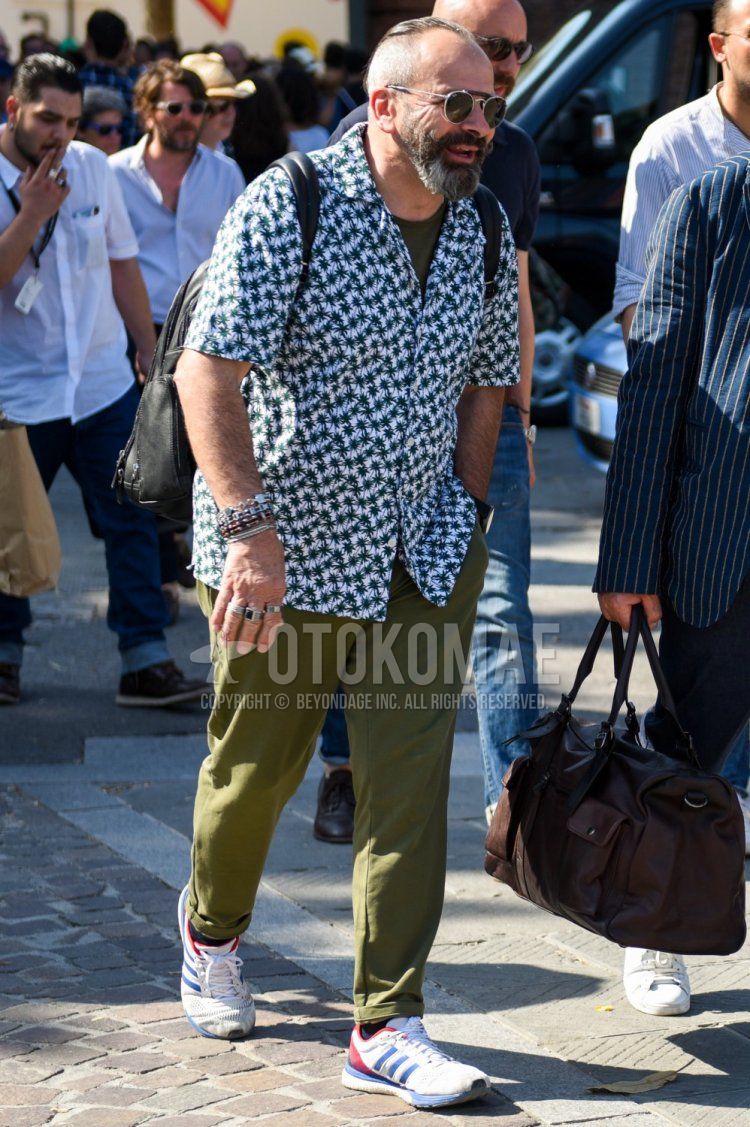 Summer men's coordinate and outfit with black/silver solid color sunglasses, white/green top/inner shirt, dark gray solid color t-shirt, olive green solid color cotton pants, black solid color socks, and white low-cut Adidas sneakers.