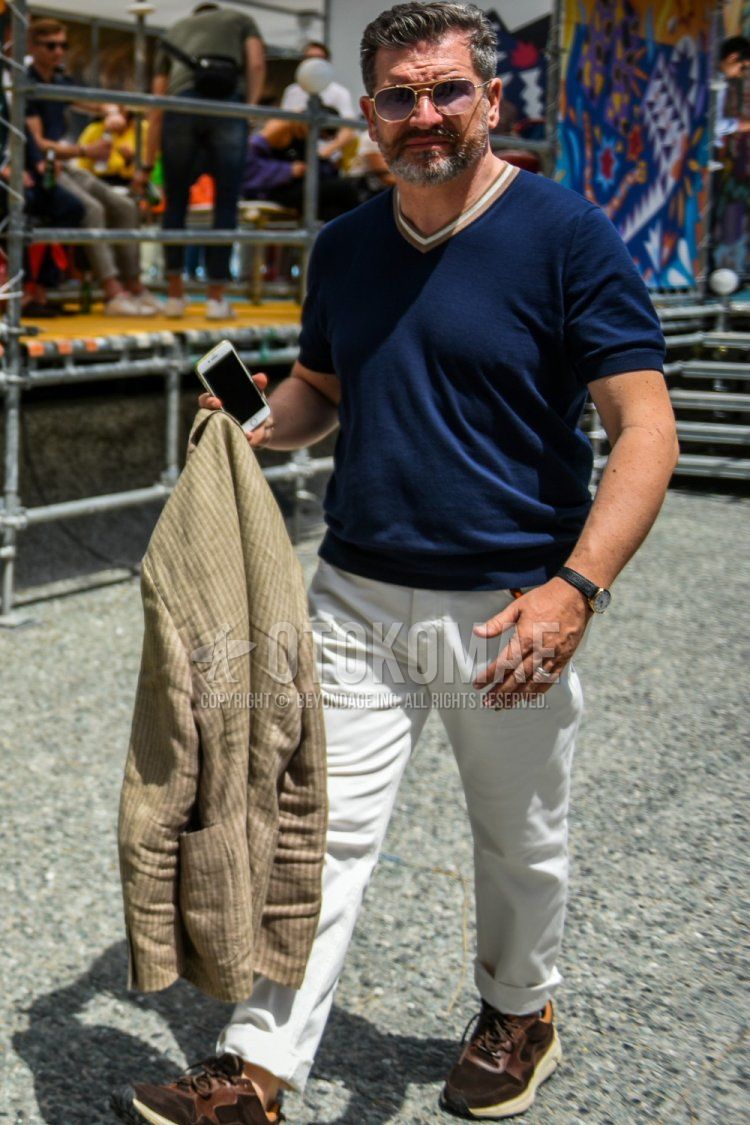 Summer men's coordinate and outfit with plain gold sunglasses, plain navy sweater, plain white cotton pants, and brown low-cut sneakers.