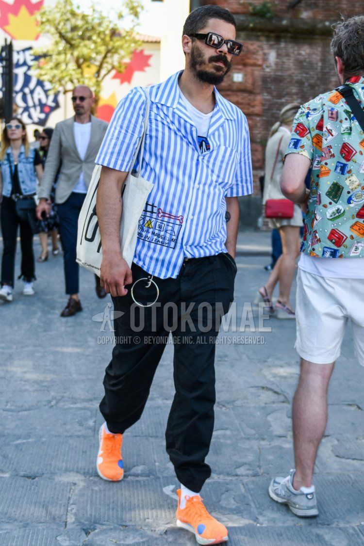 Summer men's outfit with plain black sunglasses, short-sleeved light blue striped shirt, white graphic t-shirt, plain black cotton pants, plain white socks, Nike Off White Zoom Vaporfly orange low-cut sneakers, beige graphic tote bag How to wear.