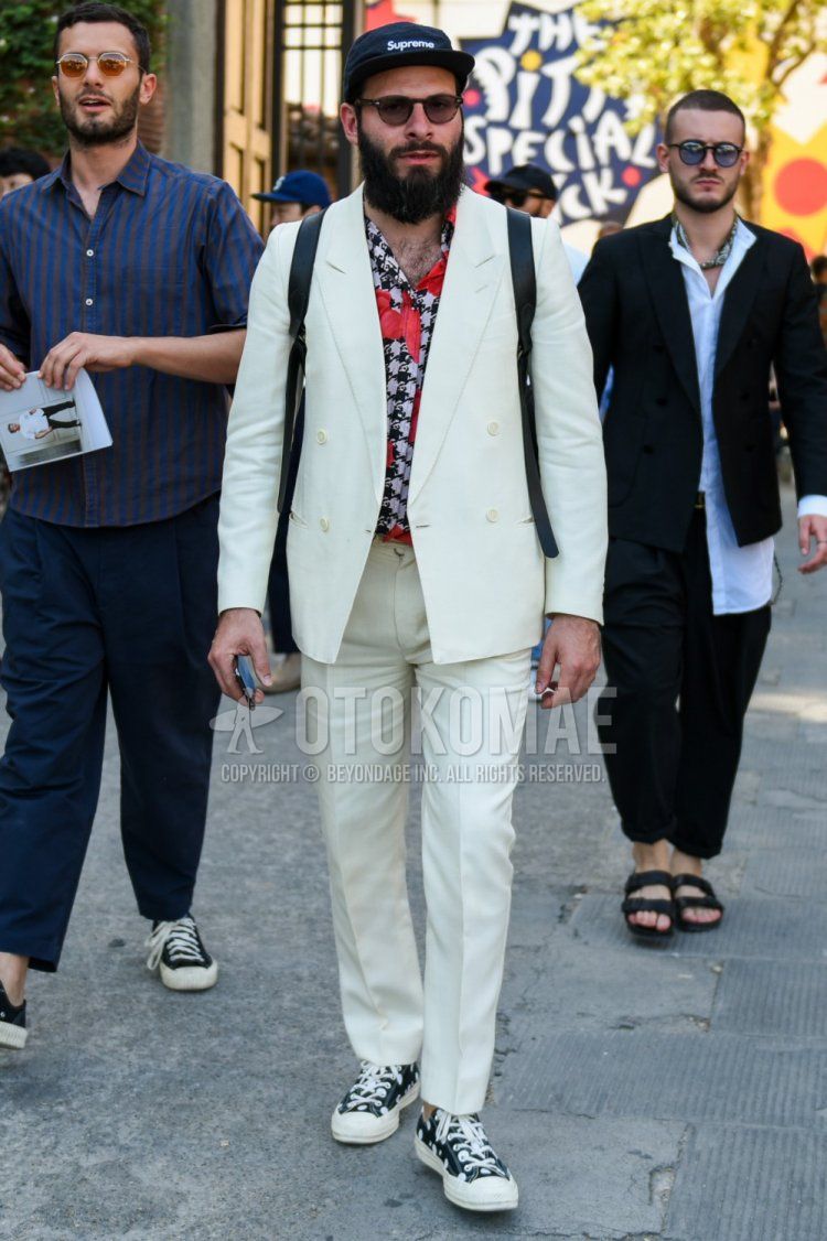 Men's spring, summer, and fall coordinate and outfit with a solid black Supreme jet cap, multi-colored top/inner shirt, black low-cut Converse sneakers, and a solid white suit.