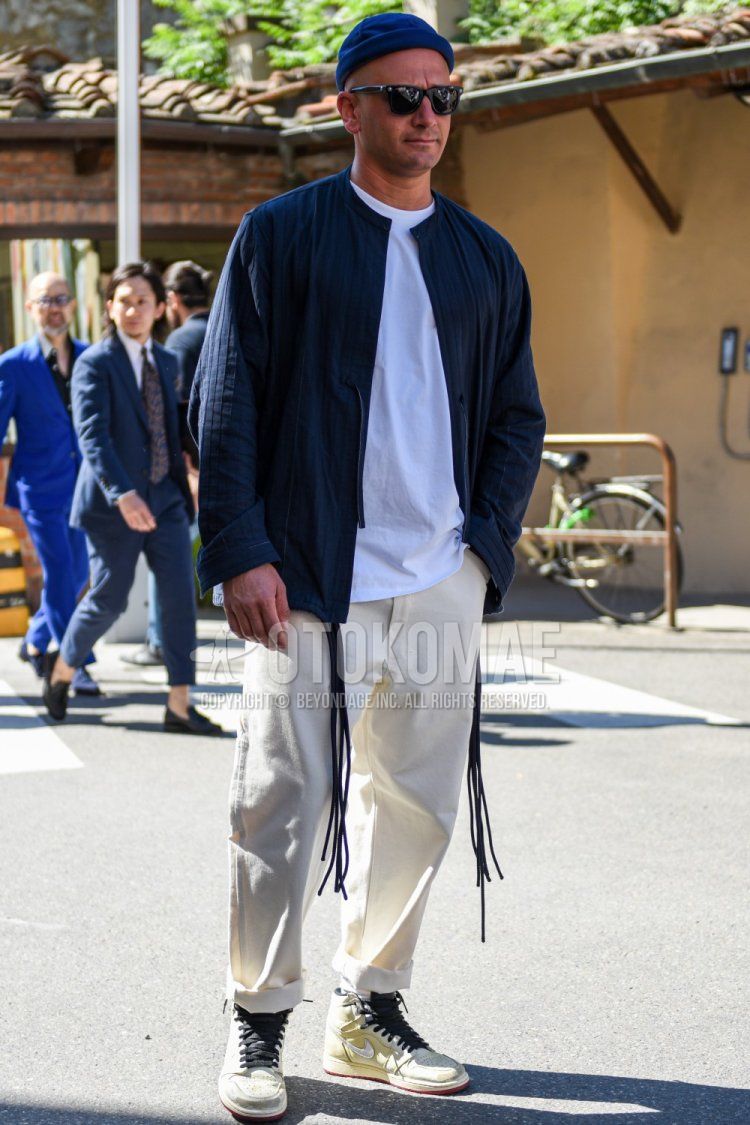 Men's spring and fall coordinate and outfit with plain navy knit cap, plain black Wellington sunglasses, plain navy shirt with no collar, plain white t-shirt, plain white cotton pants, and Nike Air Jordan 1 white high-cut sneakers.
