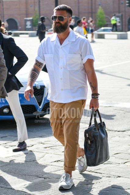Men's summer coordinate and outfit with plain silver sunglasses, plain white shirt, plain brown cotton pants, white low-cut sneakers, and plain black tote bag.