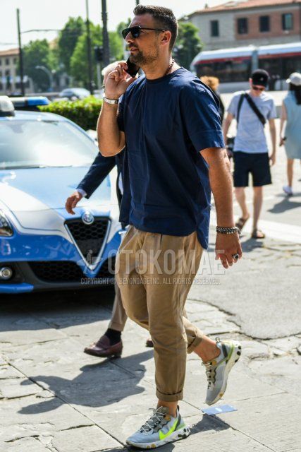 Men's summer coordinate and outfit with plain black sunglasses, plain navy t-shirt, plain brown cotton pants, and Nike gray low-cut sneakers.