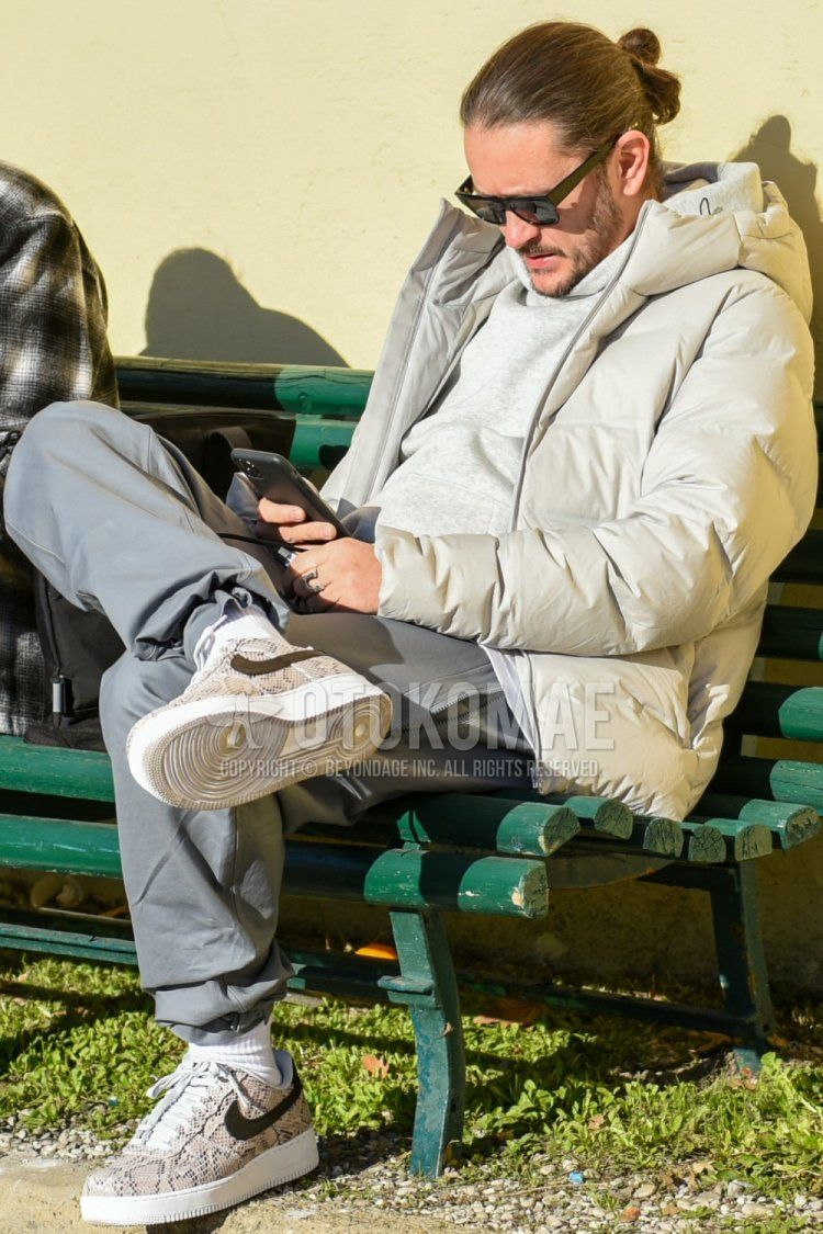 Men's fall/winter outfit with plain black sunglasses, plain white down jacket, plain gray hoodie, plain gray jogger pants/ribbed pants, plain white socks, and Nike Air Force 1 gray low-cut sneakers.