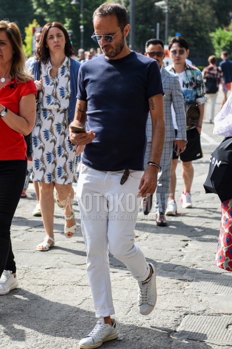 Summer men's coordinate and outfit with plain silver sunglasses, knit plain navy t-shirt, plain white denim/jeans, and white low-cut sneakers.