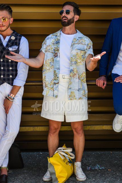Summer men's coordinate and outfit with round black and silver plain sunglasses, short sleeve open collar light blue top/inner shirt, plain white t-shirt, Gurkha plain white shorts, and Converse All Star white high cut sneakers.