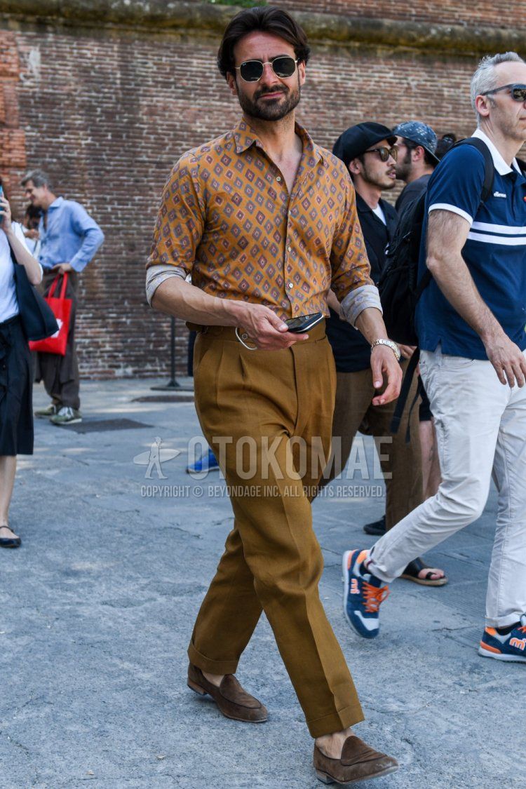 Men's spring/summer/autumn coordination and outfit with plain black/gold sunglasses, orange top/inner shirt, plain brown beltless pants, and suede brown loafer leather shoes.