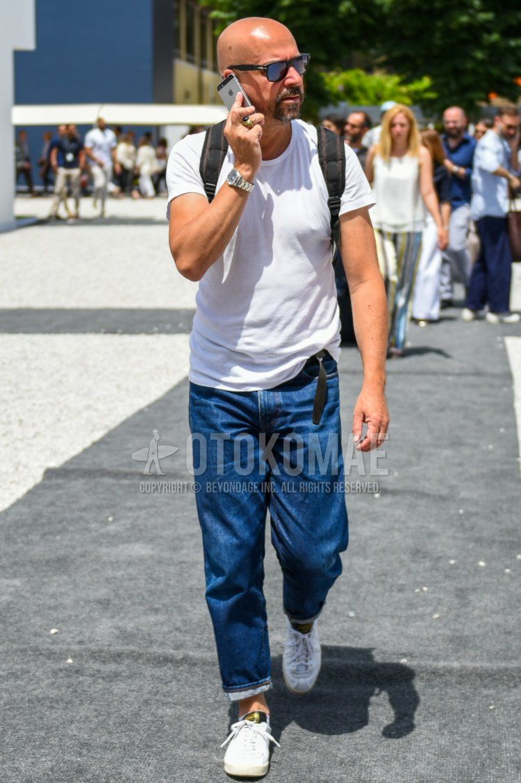 Summer men's coordinate and outfit with Persol plain black sunglasses, plain white t-shirt, plain blue denim/jeans, and white low-cut sneakers.