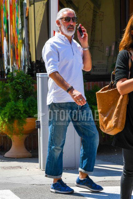 Men's spring/summer coordinate and outfit with plain black sunglasses, pullover white striped shirt, plain blue denim/jeans, and Nike blue low-cut sneakers.