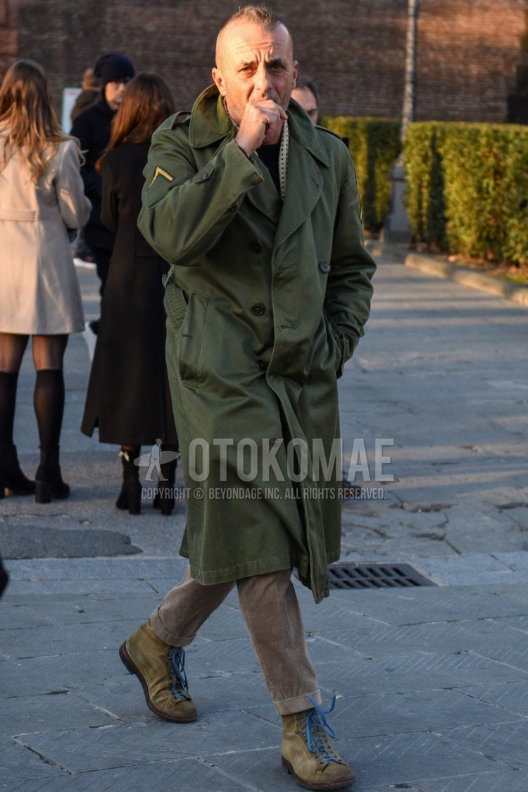 Men's fall/winter coordinate and outfit with white border scarf/stall, olive green solid trench coat, beige solid winter pants (corduroy,velour), and suede beige work boots.