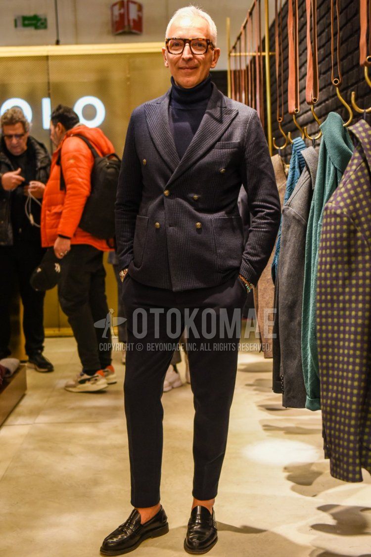 Men's spring and fall coordinate and outfit with brown tortoiseshell glasses, gray checked tailored jacket, solid gray turtleneck knit, solid gray slacks, solid gray ankle pants, and black coin loafer leather shoes.