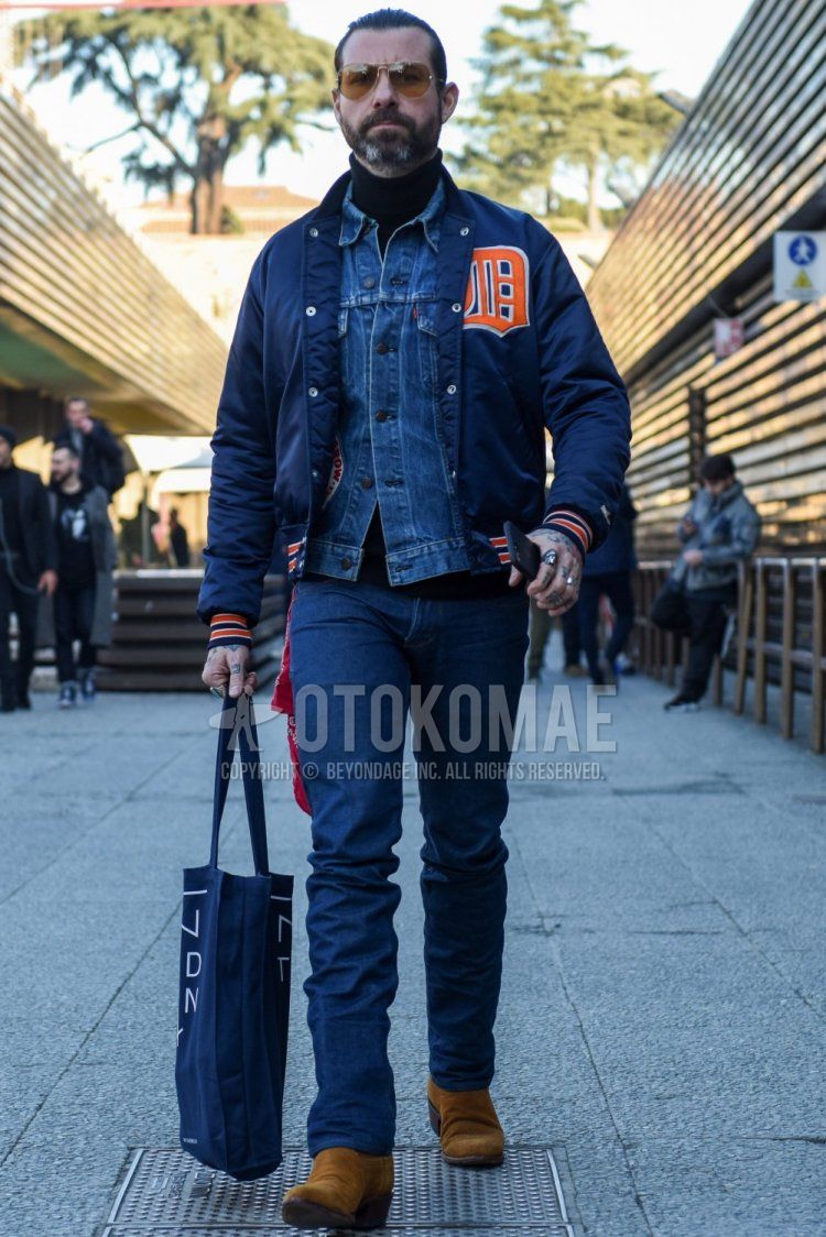 Gold solid sunglasses, navy lettered stadium jacket, Levi's blue solid denim jacket, navy solid turtleneck knit, navy solid denim/jeans, suede beige side gore boots, gray graphic tote bag for fall/winter. Men's Codes and Outfits.