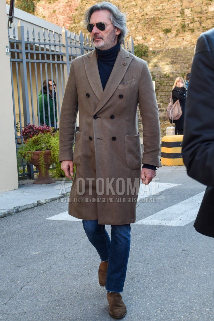 Men's fall/winter outfit with Ray-Ban aviator teardrop solid gold sunglasses, Lardini solid beige chester coat, dark gray solid turtleneck knit, blue solid denim/jeans, and suede beige boots.
