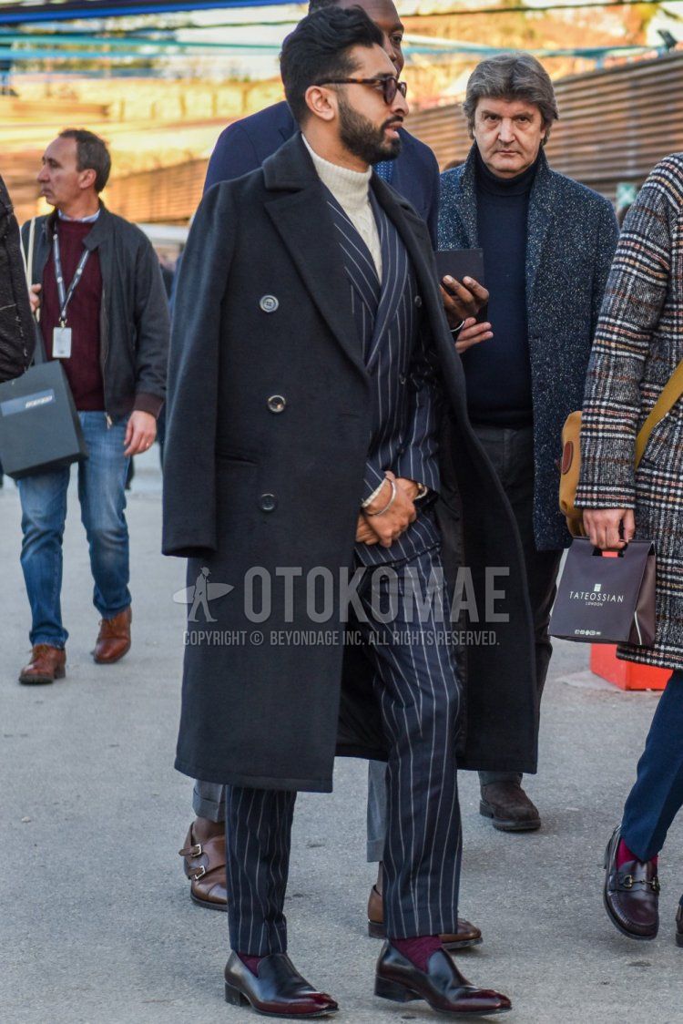 Men's fall/winter coordinate and outfit with brown tortoiseshell sunglasses, plain navy Ulster coat, plain white turtleneck knit, plain red socks, brown loafer leather shoes, and gray striped suit.