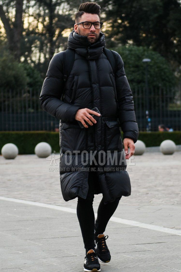 Men's fall/winter coordinate and outfit with plain black glasses, plain black down jacket, plain black skinny pants, and black low-cut sneakers.