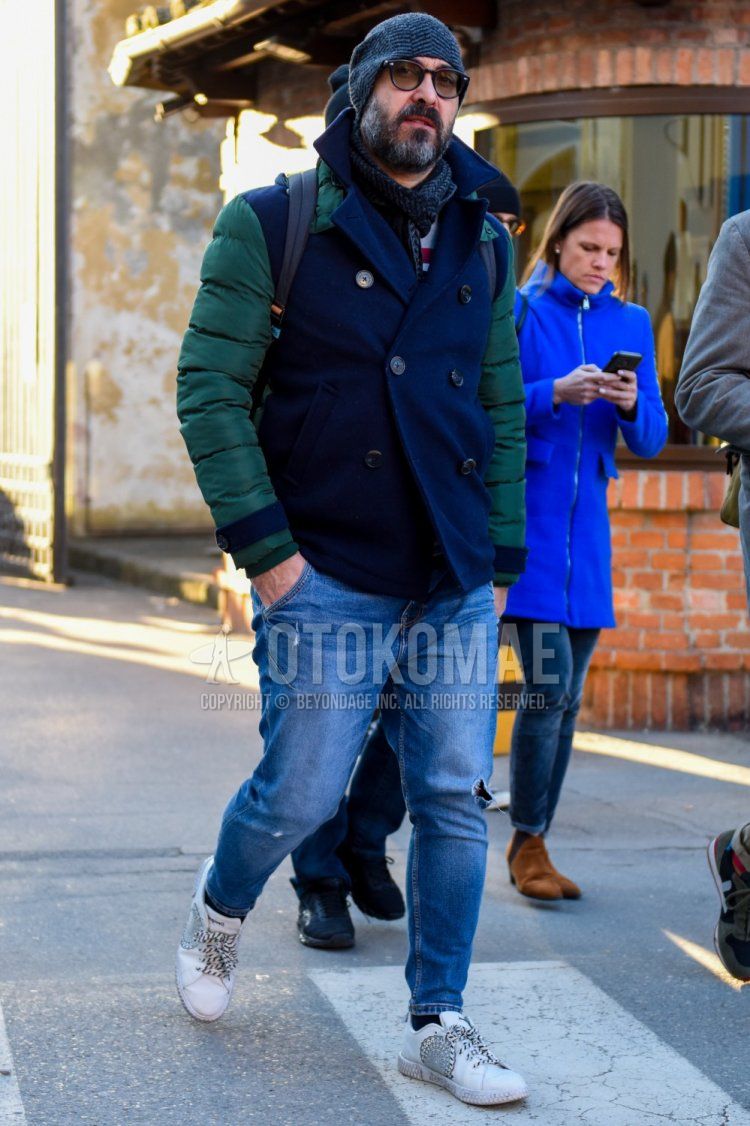 Men's fall/winter outfit with gray cap knit cap, solid black sunglasses, gray herringbone scarf/stall, solid olive green P coat, solid navy down jacket, solid blue damaged jeans, solid black socks, white low-cut sneakers Outfit.