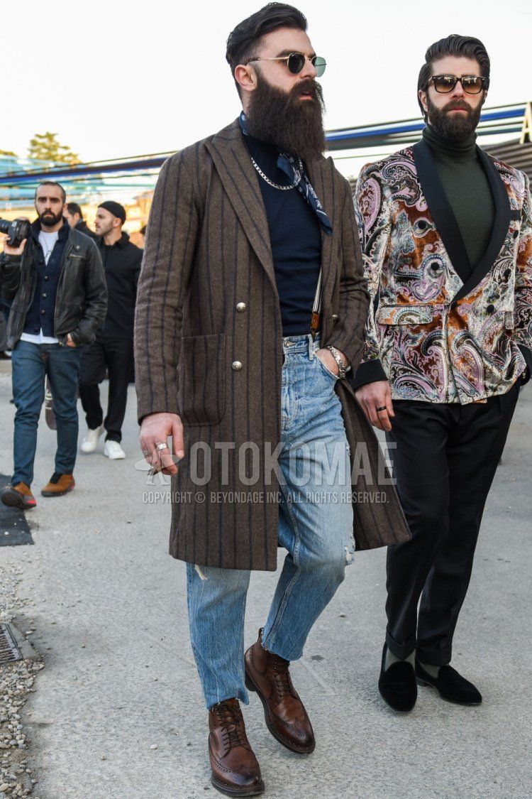 Men's fall/winter outfit with Ray-Ban gold solid sunglasses, navy paisley bandana/neckerchief, brown striped chester coat, navy solid sweater, blue solid denim/jeans, blue solid cropped pants, brown boots.