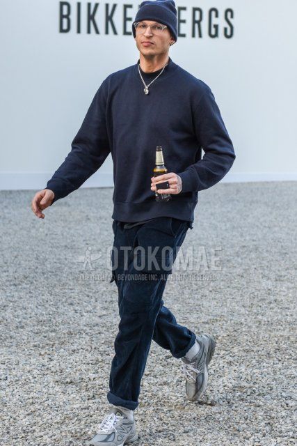 Men's spring and fall outfit with dark gray solid color knit cap, clear solid color glasses, dark gray solid color sweatshirt, dark gray solid color cargo pants, white solid color socks, and New Balance gray low-cut sneakers.
