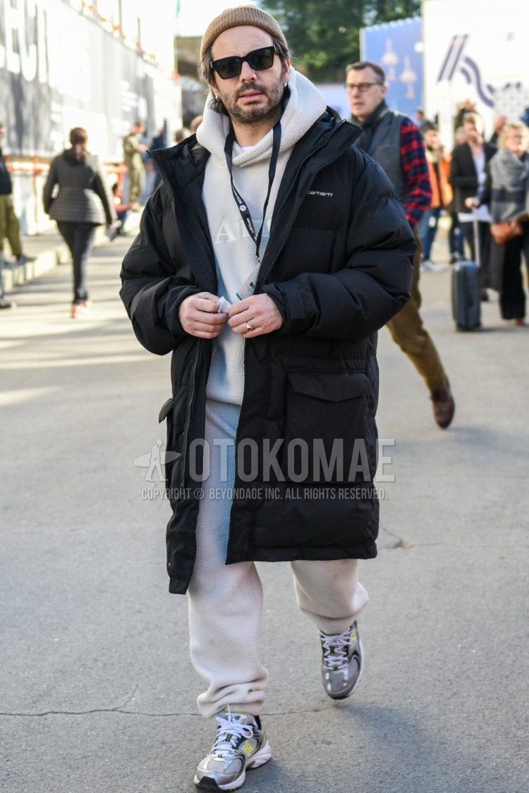 Winter men's coordinate and outfit with beige solid color knit cap, Wellington solid color black sunglasses, Carhartt solid color black down jacket, gray low cut sneakers, and white solid color casual setup.