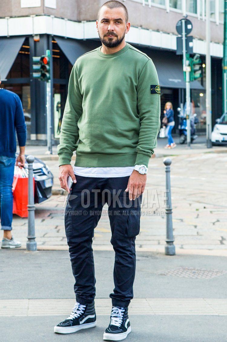 Men's spring and fall coordinate and outfit with Stone Island plain green sweatshirt, plain white t-shirt, dark gray plain cargo pants, and Vans Skate High black high-cut sneakers.