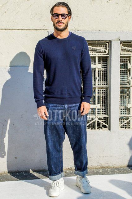 Men's spring/autumn coordinate and outfit with solid black sunglasses, solid navy sweater, solid blue denim/jeans, solid white socks, and white low-cut sneakers.